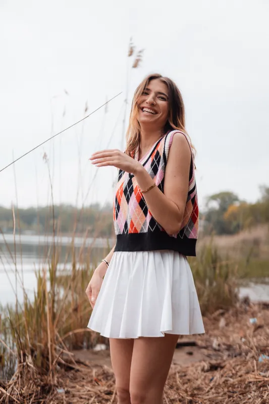 Argyle knit vest and white skirt, laughing among the reeds