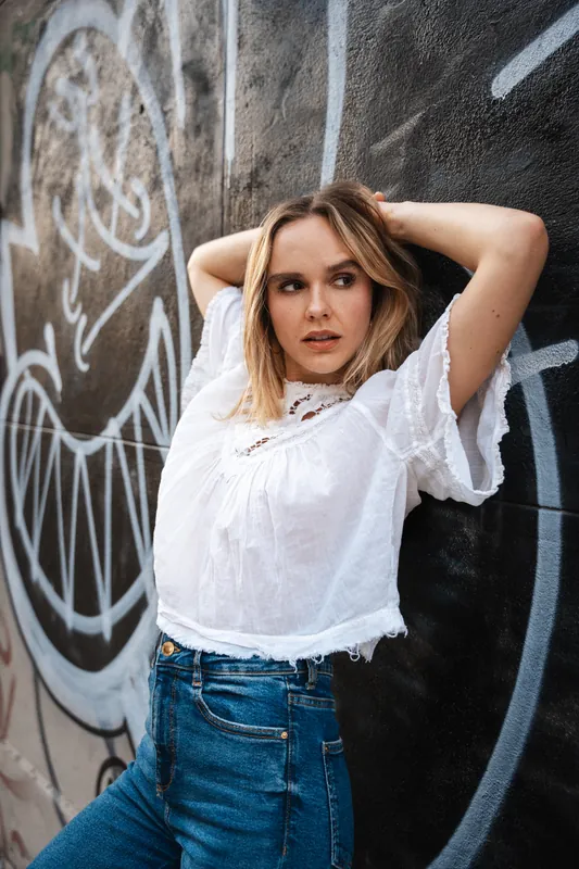 White cropped blouse and jeans against a graffiti wall
