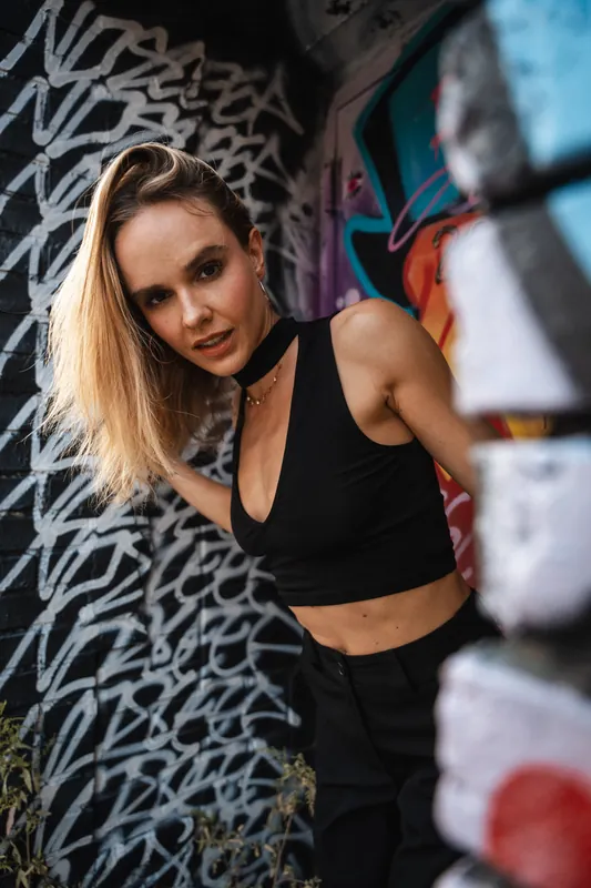 Black crop top leaning into a graffiti covered alley wall