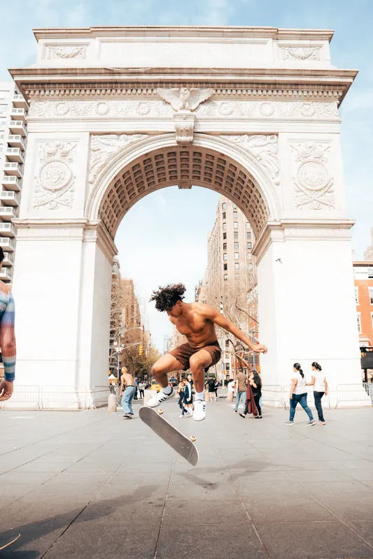 Skateboarder mid air under the Washington Square Arch