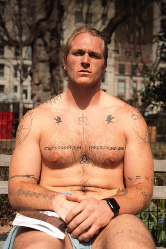 Tattooed man on a park bench in hard sun