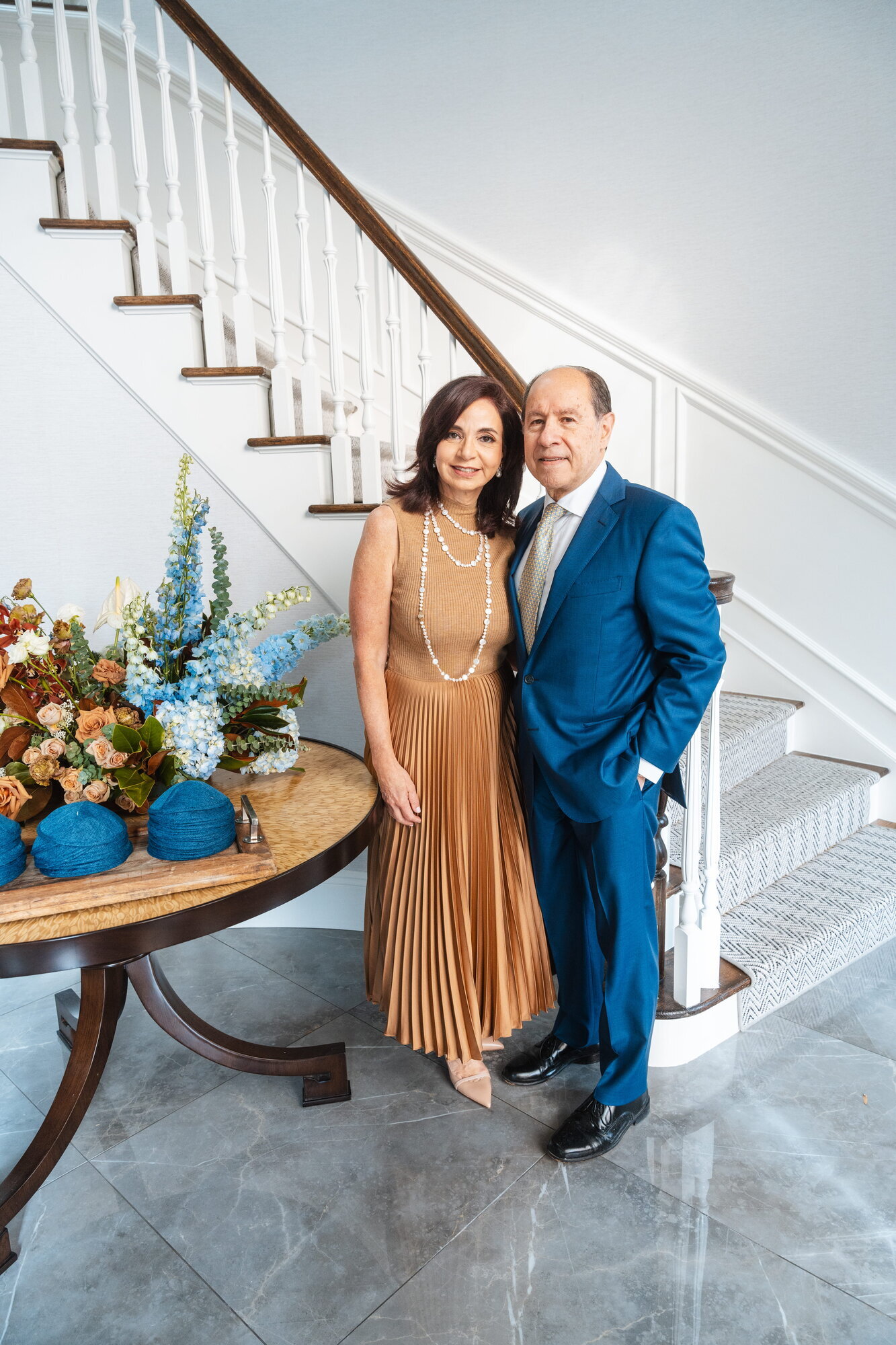 Hosts in formal wear on a staircase at a bris celebration