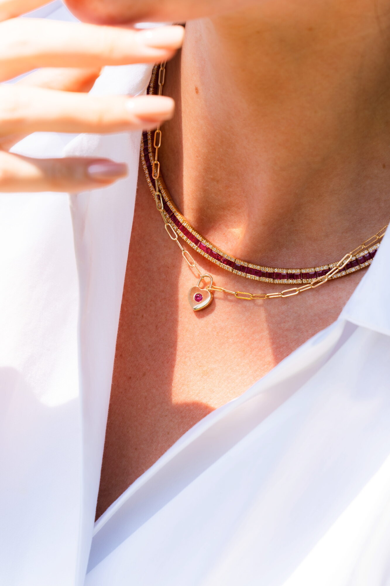 Detail of layered EFFY gold and garnet bead necklaces with a gemstone pendant against a white shirt