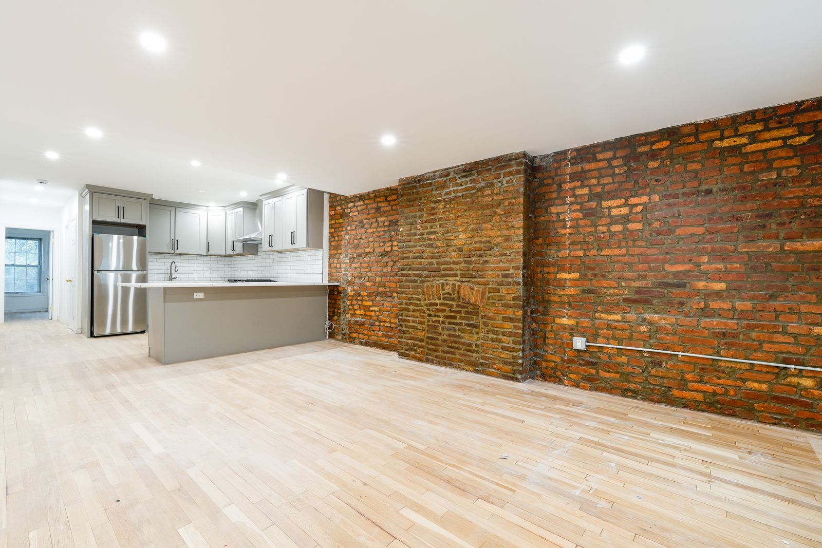 Before: an open living room with an exposed brick wall, empty