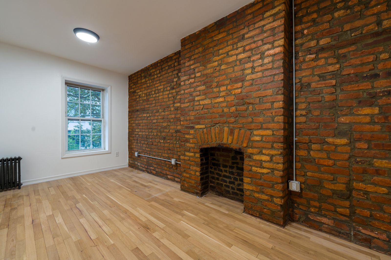 Before: a bedroom with an exposed brick fireplace, empty